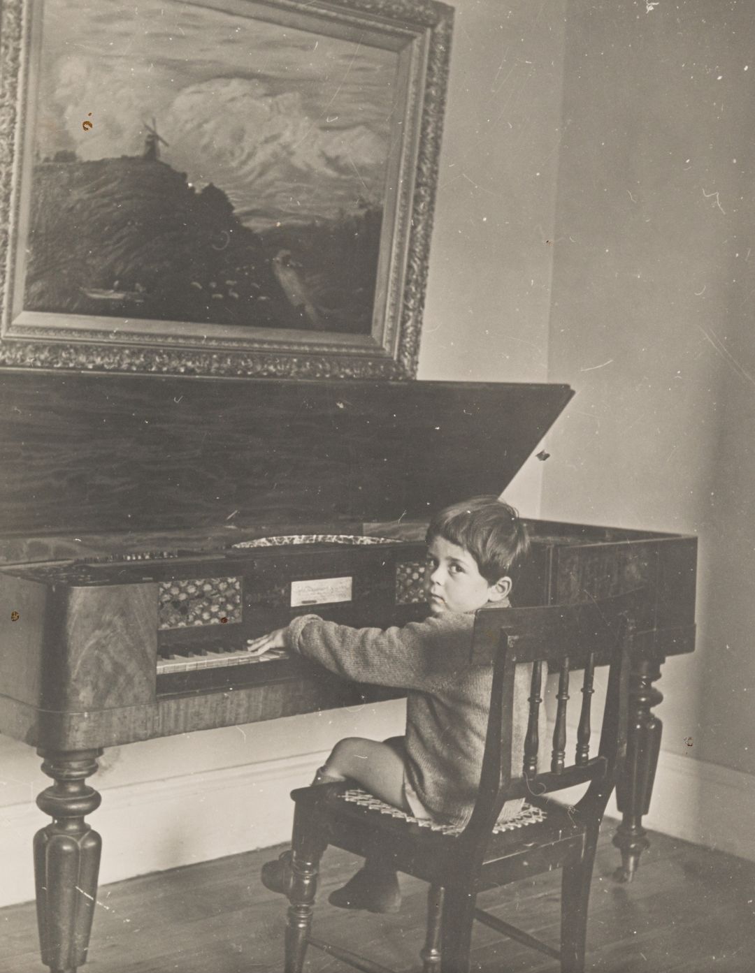 Black and white photo of a young Leopold Podlashuc sitting by a piano